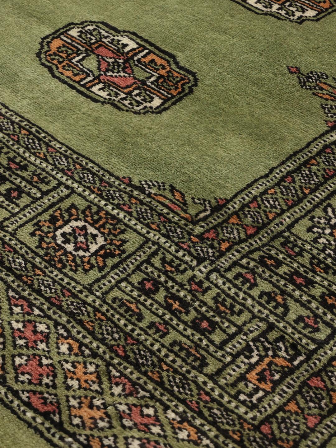 Hand-knotted Pakistan Bokhara runner in green with traditional geometric motifs.