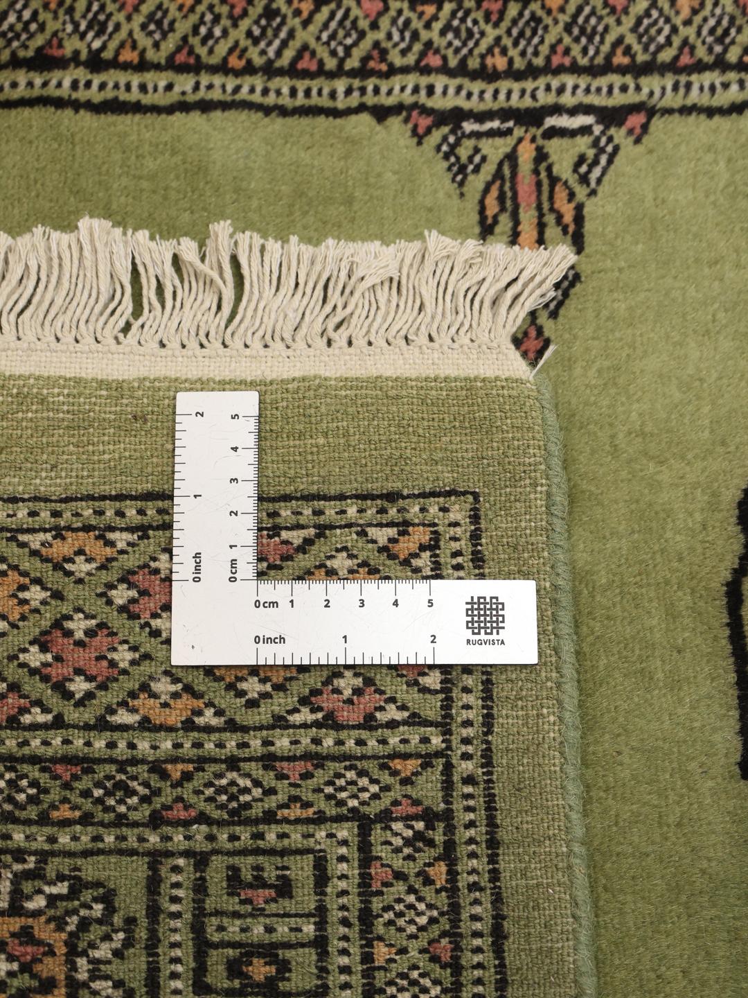 Hand-knotted Pakistan Bokhara runner in green with traditional geometric motifs.
