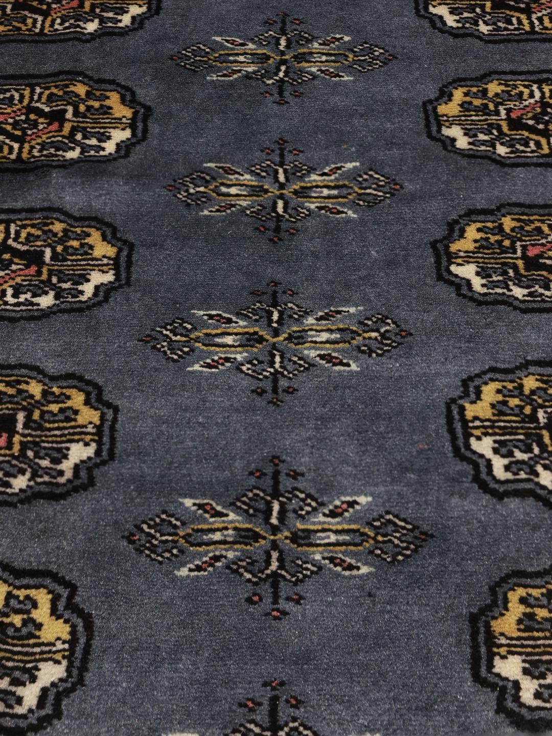 A hand-knotted Pakistan Bokhara rug in grey with traditional medallion motifs.