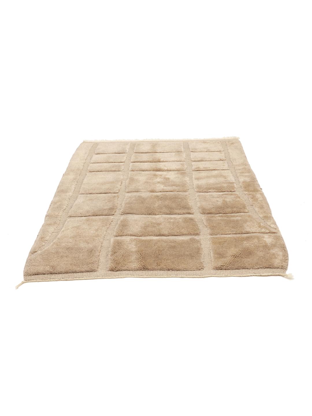 Un tapis berbère marocain noué à la main en beige avec un motif de grille géométrique.
