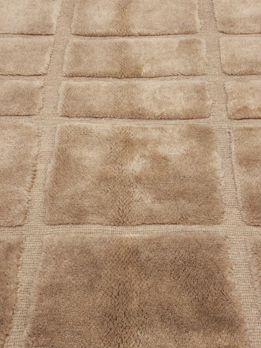 Un tapis berbère marocain noué à la main en beige avec un motif de grille géométrique.