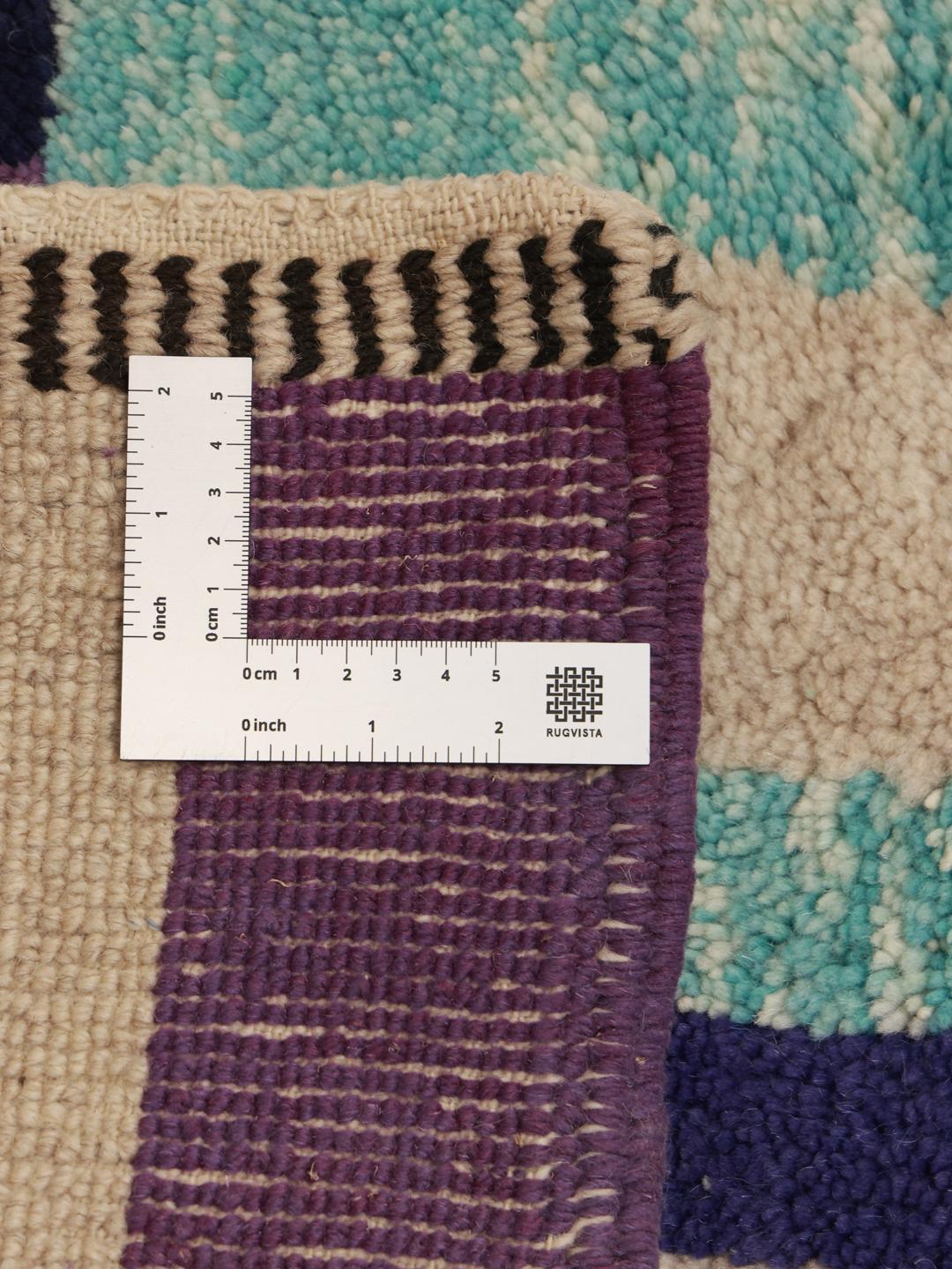 Håndknyttet marokkansk løber med abstrakte lilla, blå og sorte geometriske mønstre på en beige baggrund.