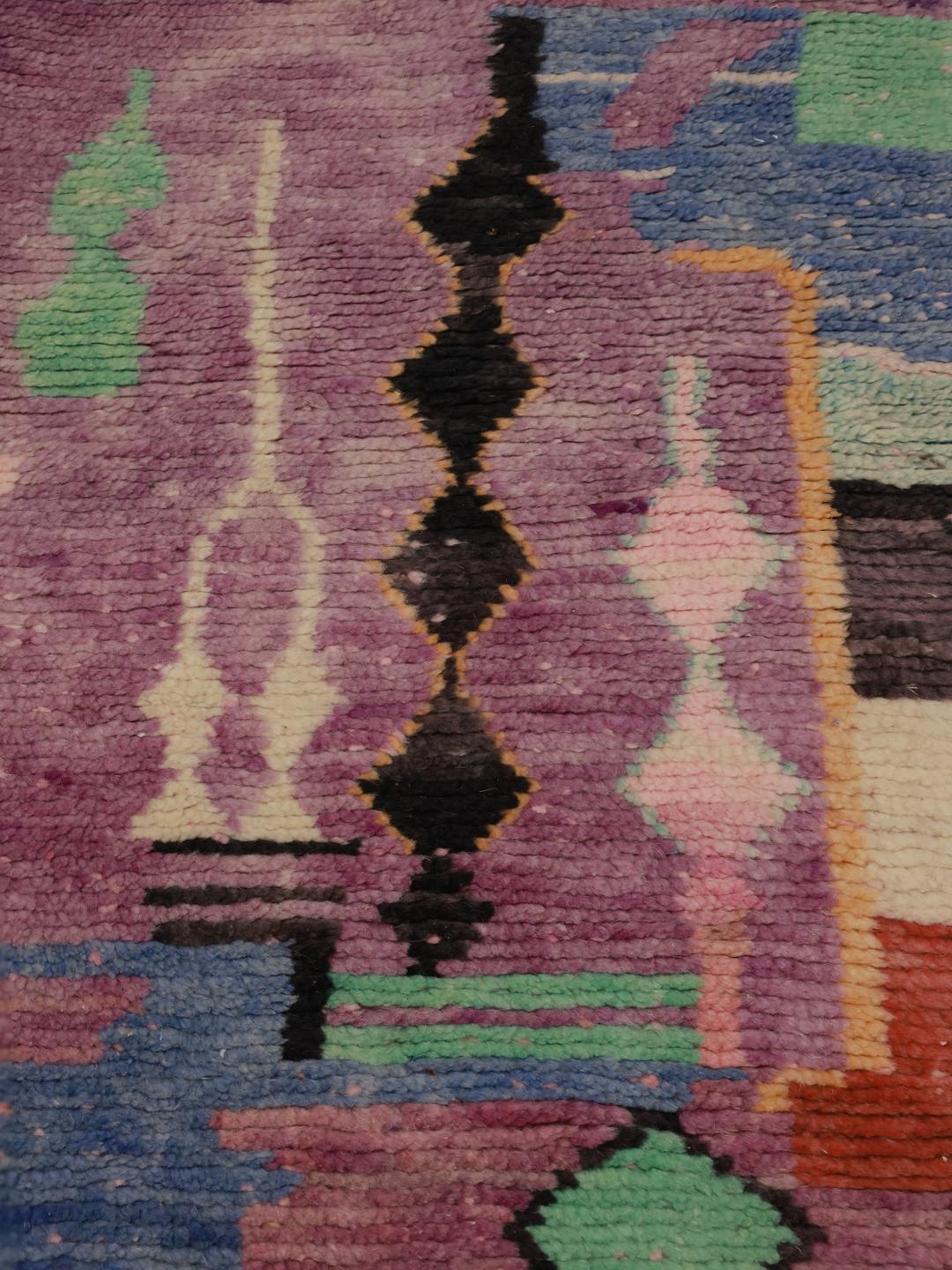 Een levendig paars Marokkaans tapijt met artistieke geometrische motieven en een hoogpolige wollen textuur.