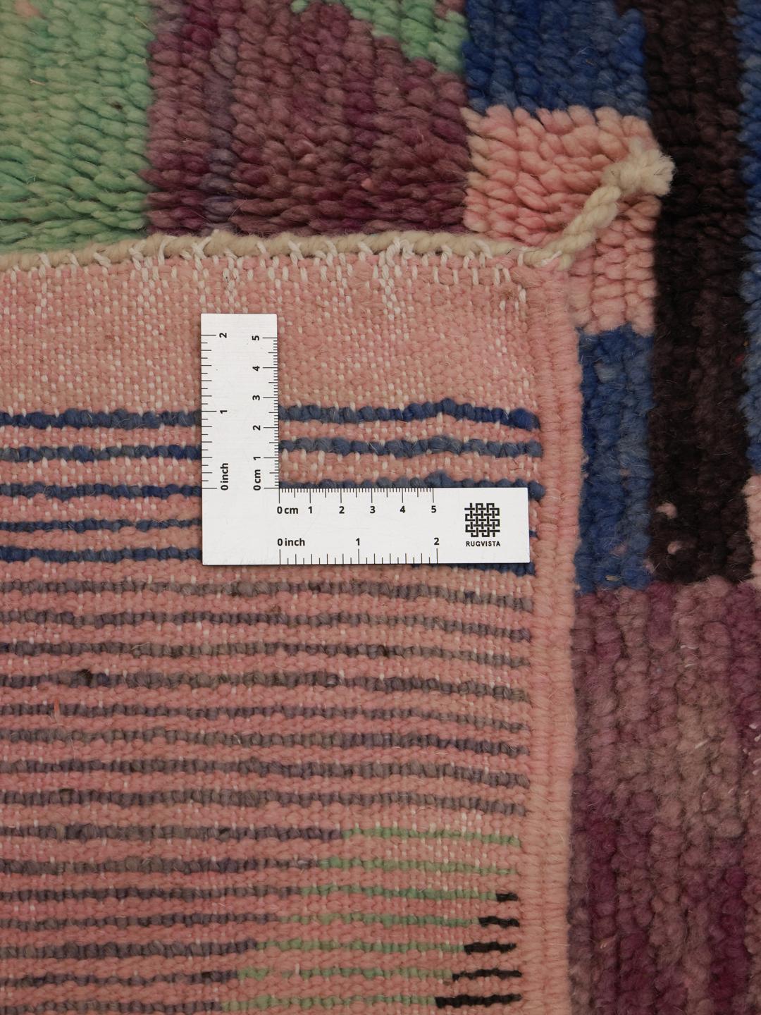 Een levendig paars Marokkaans tapijt met artistieke geometrische motieven en een hoogpolige wollen textuur.