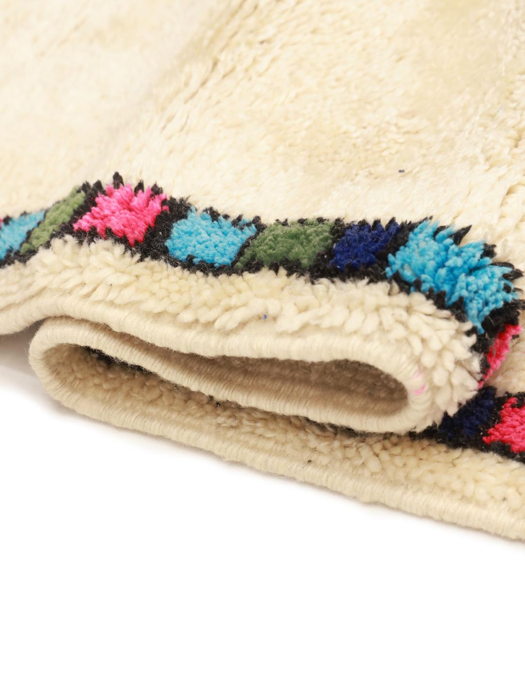 Een met de hand geknoopt Berber Marokkaans tapijt met een geometrisch ruitpatroon in blauw en zwart op een beige wollen achtergrond.