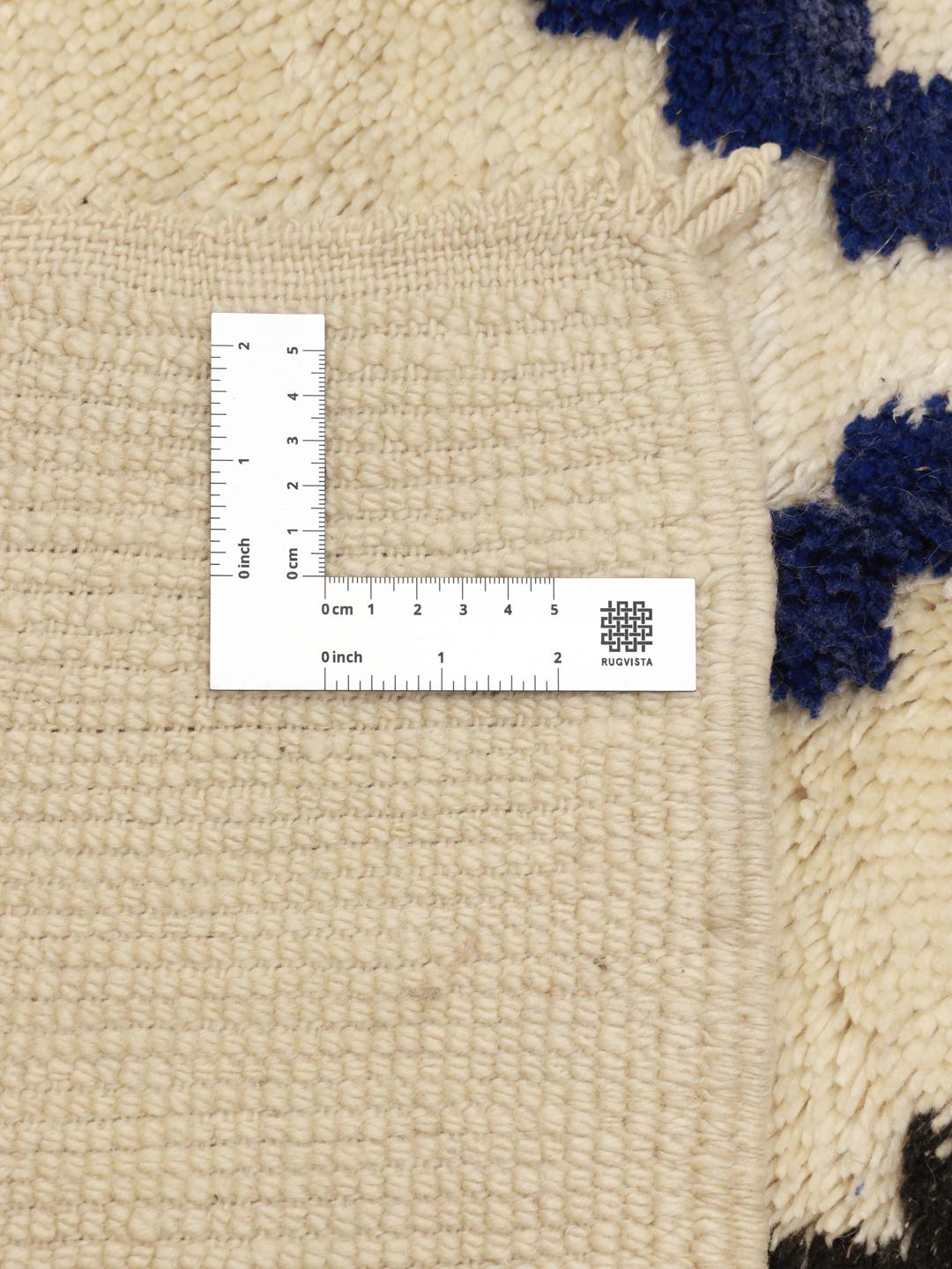 Een met de hand geknoopt Berber Marokkaans tapijt met een geometrisch ruitpatroon in blauw en zwart op een beige wollen achtergrond.