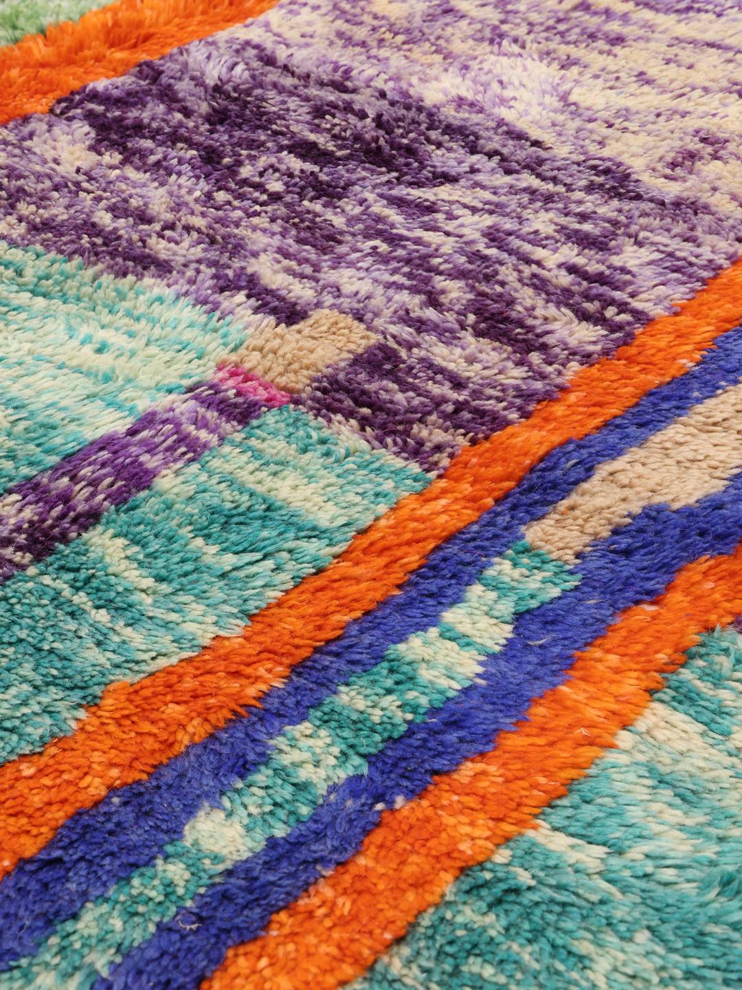 Een groot, handgeknoopt Marokkaans tapijt met een abstract, veelkleurig geometrisch patroon.