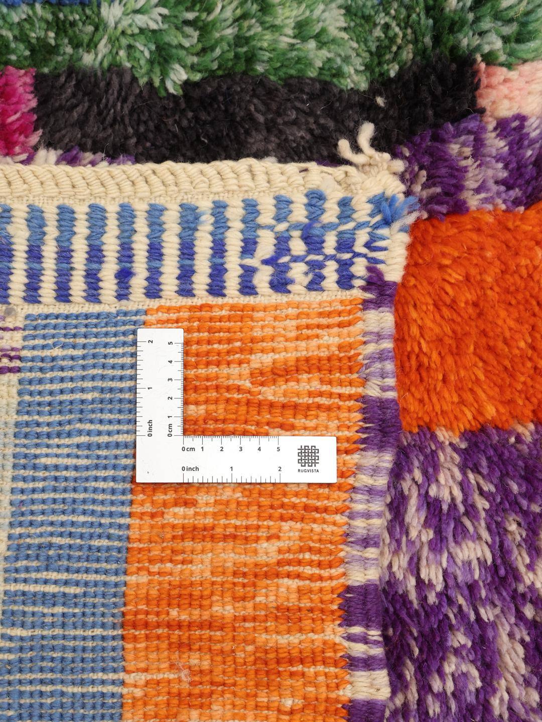 Een groot, handgeknoopt Marokkaans tapijt met een abstract, veelkleurig geometrisch patroon.