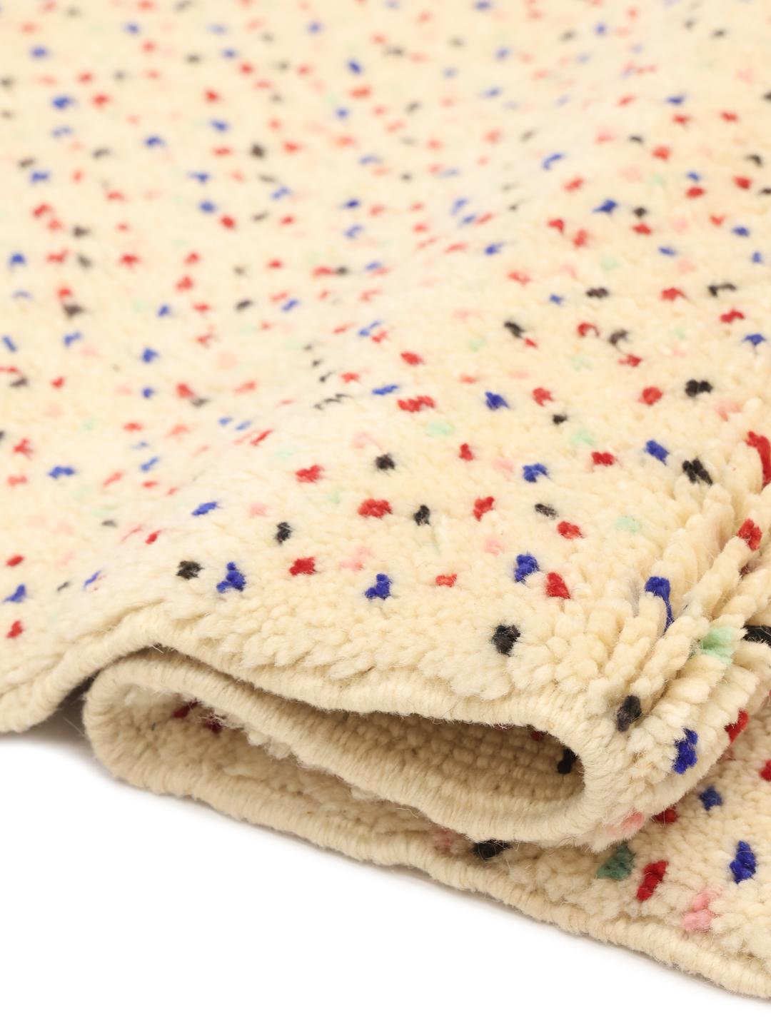 Handgemaakt Berber Marokkaans tapijt met meerkleurige spikkels op een beige achtergrond.