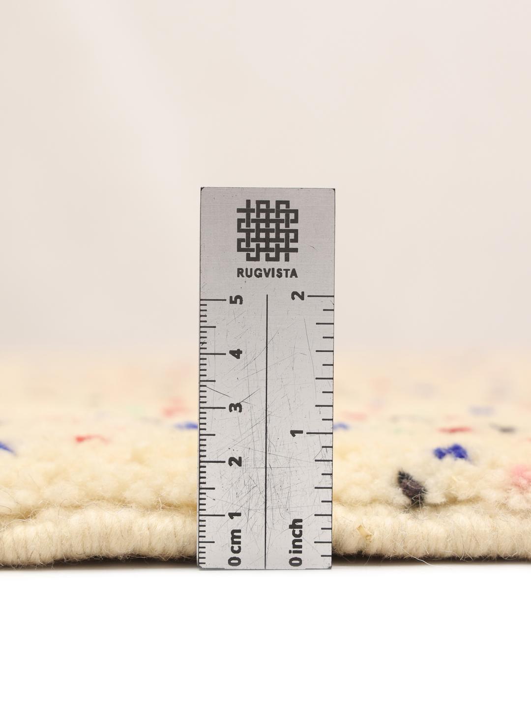 Handgemaakt Berber Marokkaans tapijt met meerkleurige spikkels op een beige achtergrond.