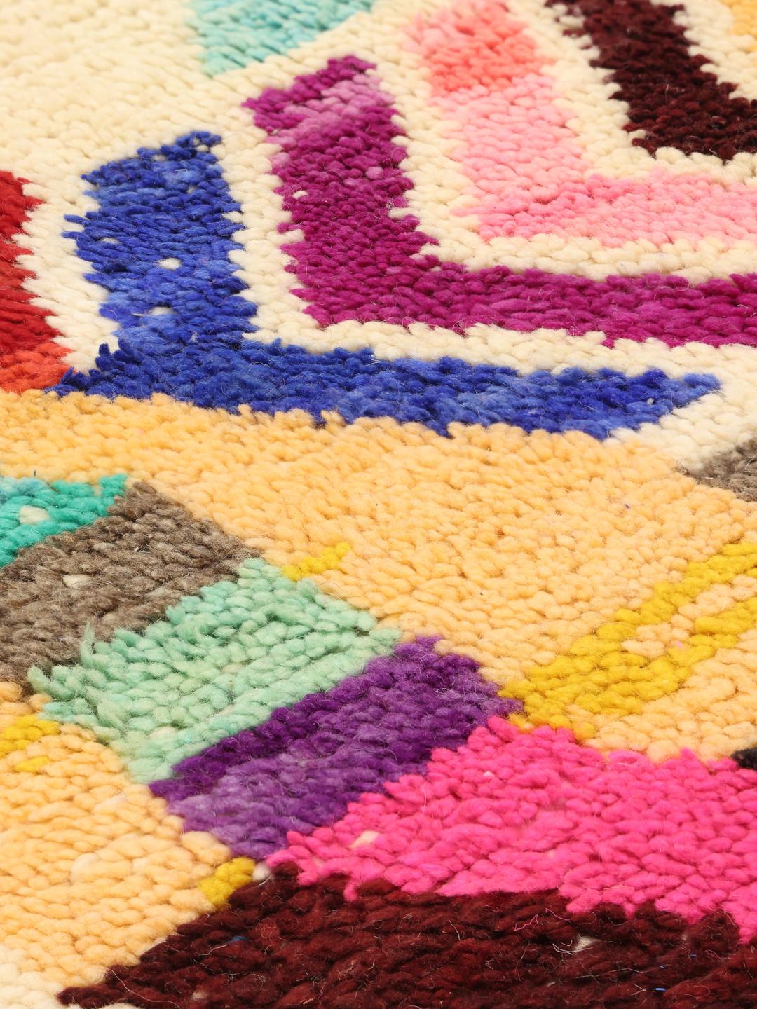 Un tapis berbère marocain vibrant, noué à la main, avec des formes géométriques et des couleurs multiples.