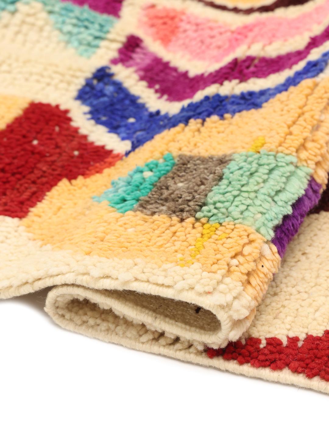 Un tapis berbère marocain vibrant, noué à la main, avec des formes géométriques et des couleurs multiples.