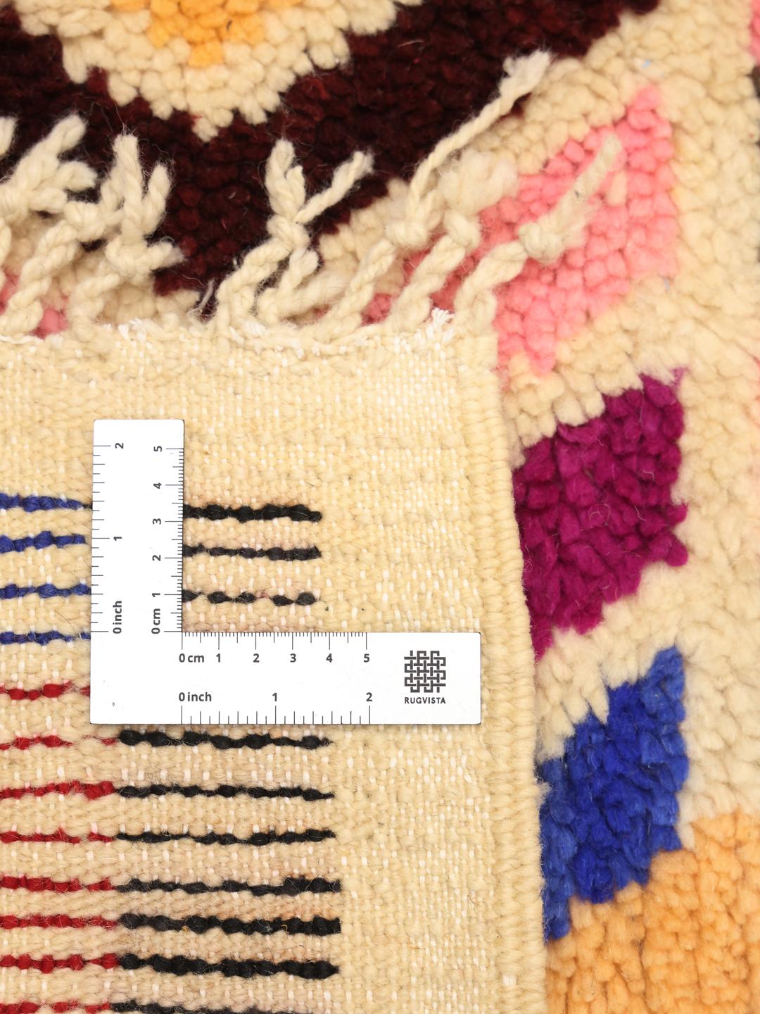 Un tapis berbère marocain vibrant, noué à la main, avec des formes géométriques et des couleurs multiples.