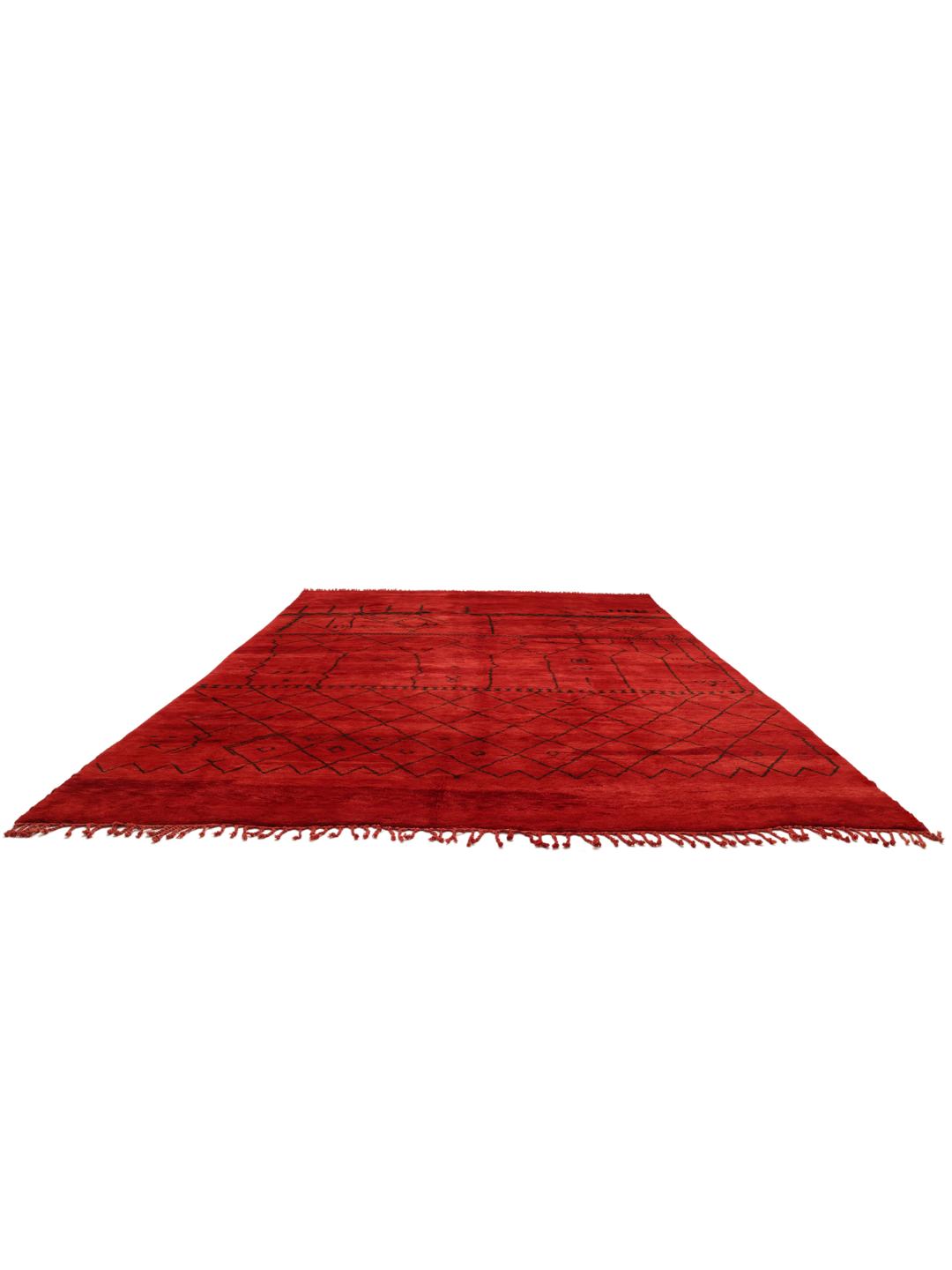 Een groot handgeknoopt Marokkaans tapijt met een levendig rood veld en donkere geometrische patronen.