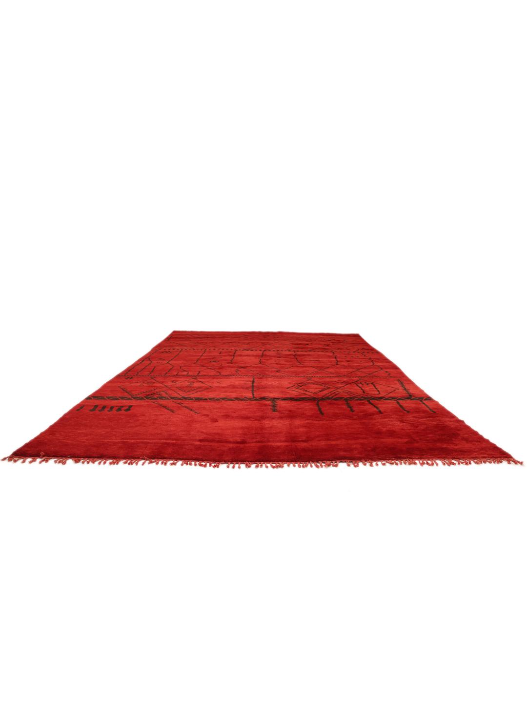 Een groot handgeknoopt Marokkaans tapijt met een levendig rood veld en donkere geometrische patronen.