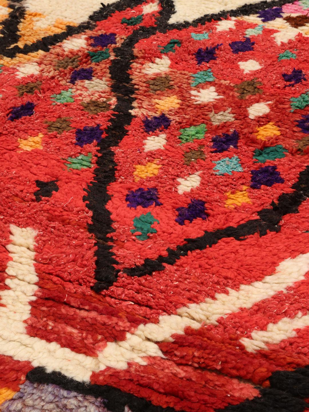 Een levendig, handgeknoopt Berber Marokkaans tapijt met gedurfde geometrische patronen in veelkleurige wol.