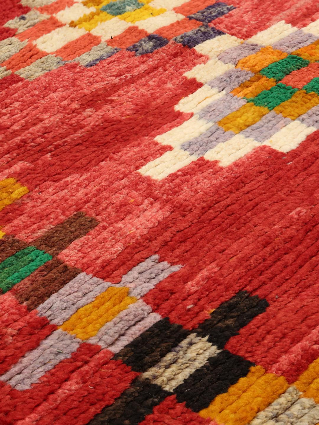 Een levendig handgeknoopt Marokkaans tapijt met geometrische patronen in veelkleurige wol