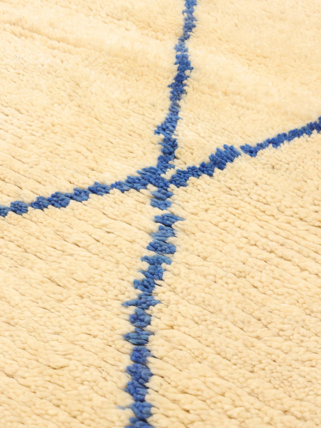 Tapis berbère marocain noué à la main avec une base beige et un motif géométrique en losanges bleus