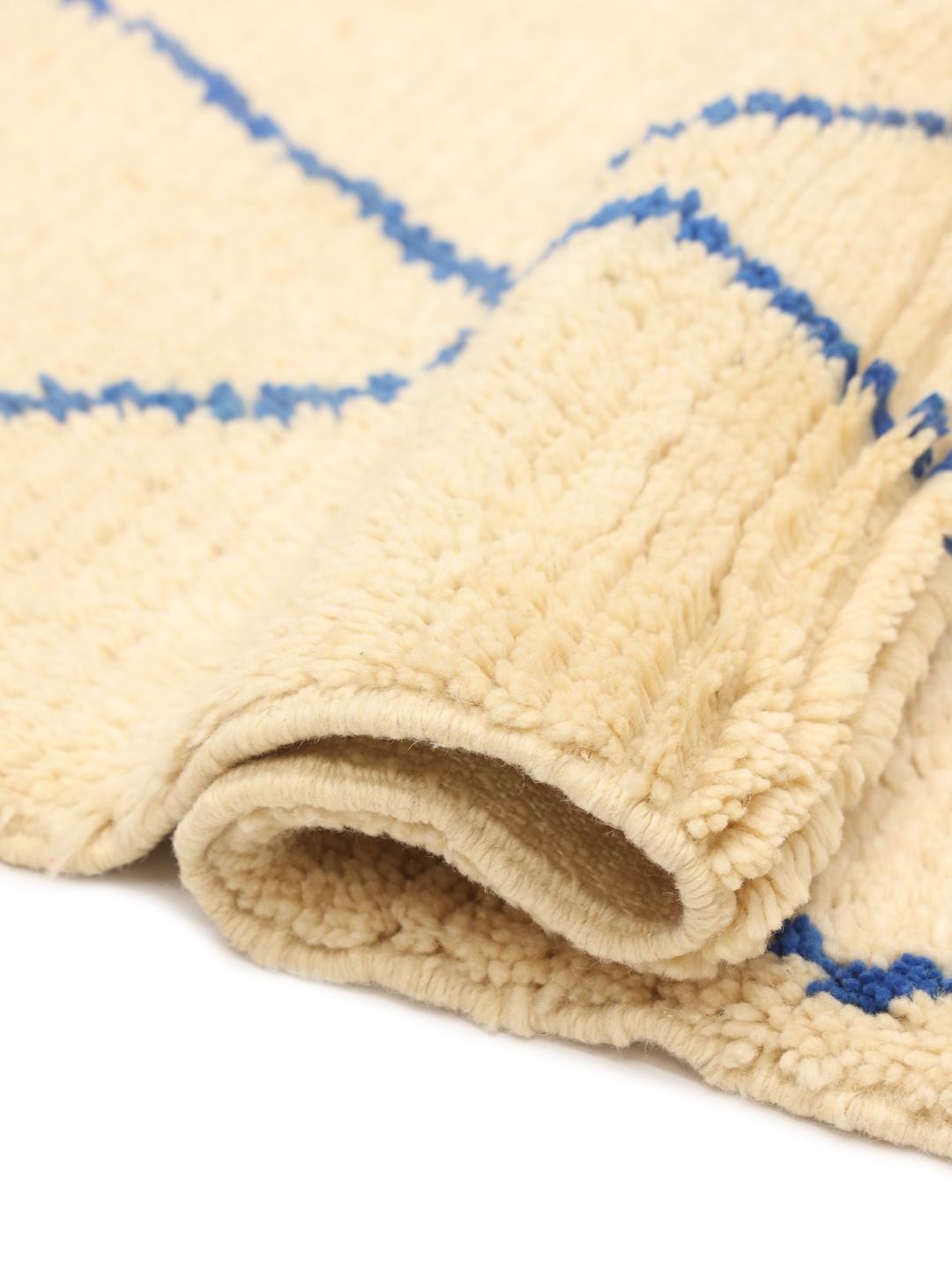 Tapis berbère marocain noué à la main avec une base beige et un motif géométrique en losanges bleus