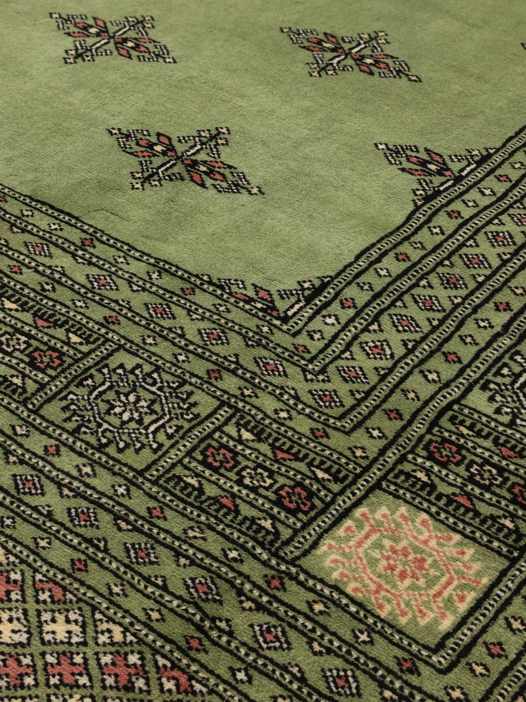 Hand-knotted Bokhara rug from Pakistan with a soft green field