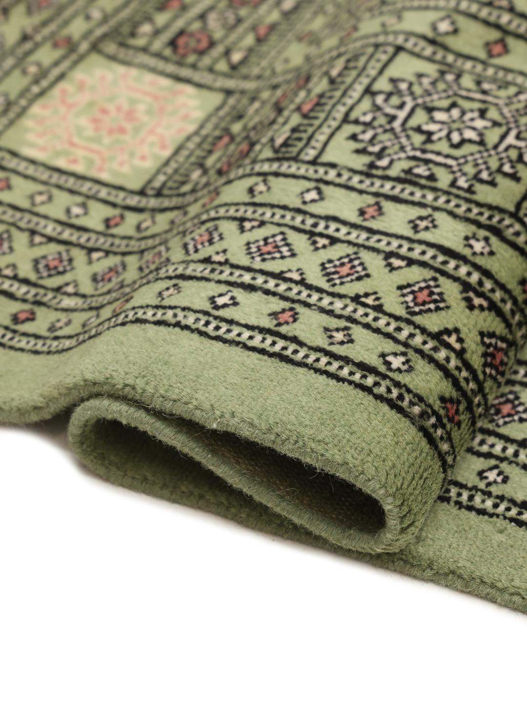 Hand-knotted Bokhara rug from Pakistan with a soft green field