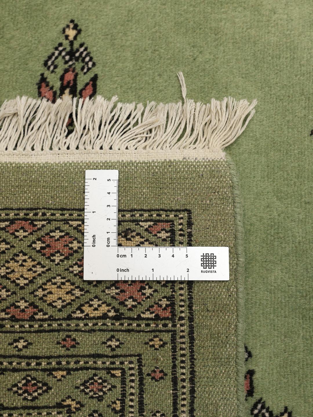 Hand-knotted Bokhara rug from Pakistan with a soft green field
