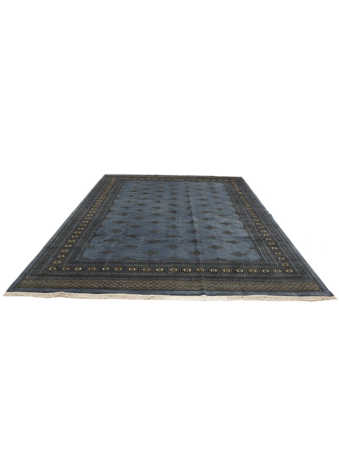 A hand knotted Bokhara rug from Pakistan in a soft blue color with intricate repeating motifs.