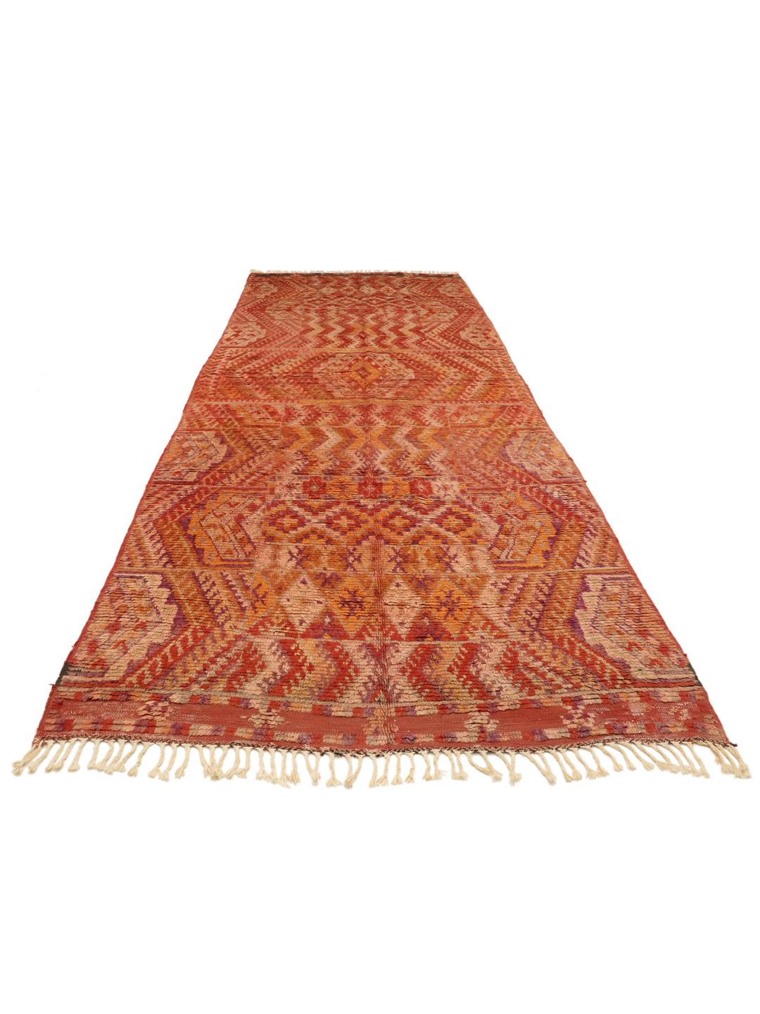 En vintage marokkansk løber med komplekse geometriske mønstre i nuancer af rød og orange.