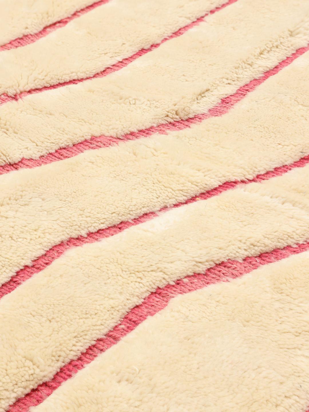 Een groot rechthoekig Marokkaans Beni Ouarain tapijt met een crèmekleurige achtergrond en een roze verticaal gestreept ontwerp.