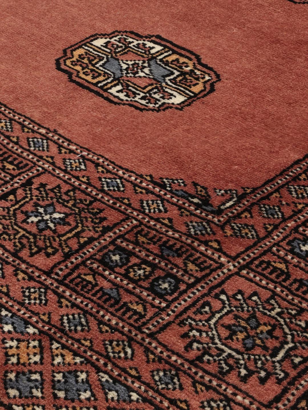 Et håndknyttet Bokhara-tæppe fra Pakistan i en rig mørkerød tone med gentagne gul-motiver.