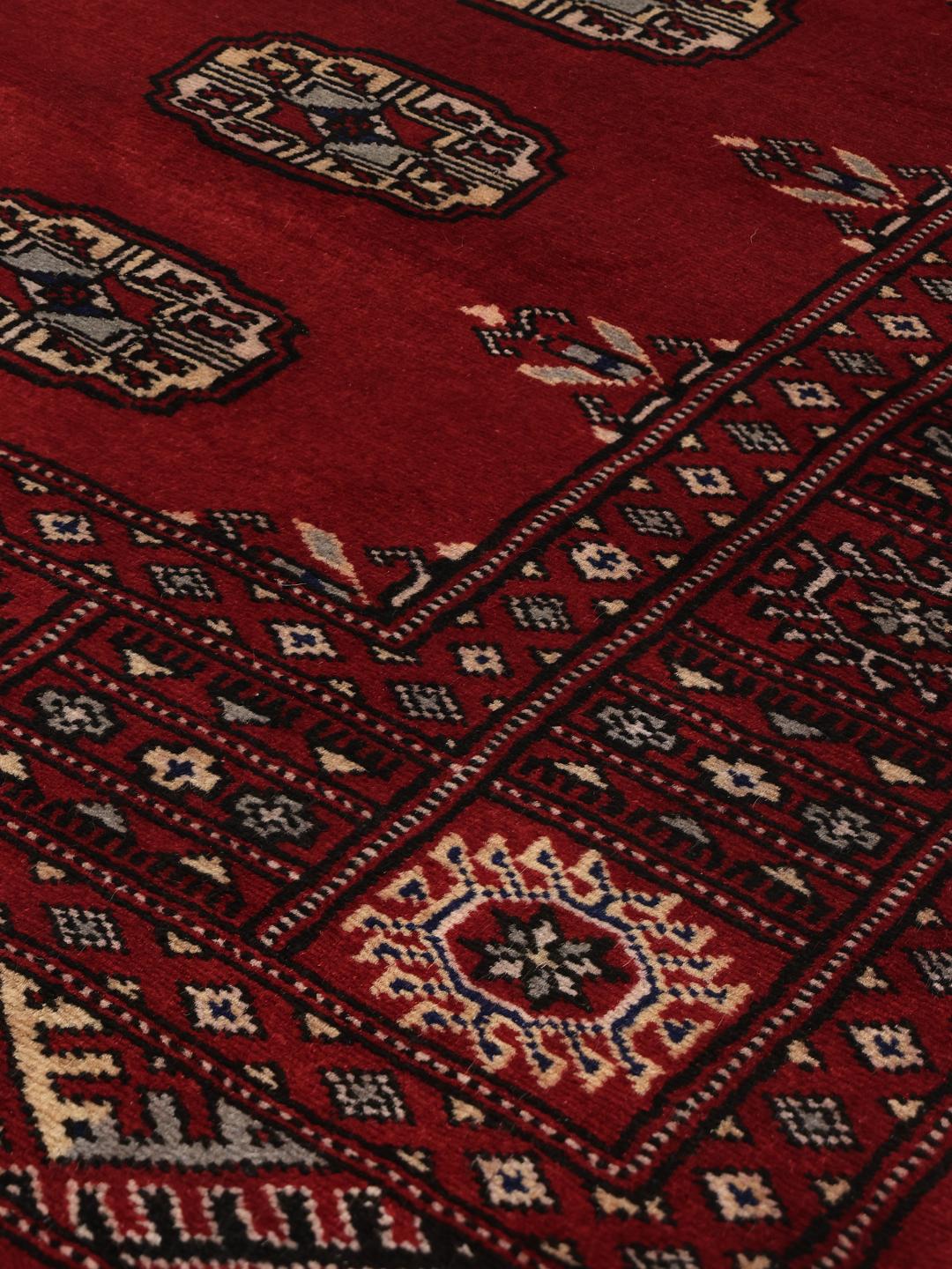 Hand-knotted Pakistani Bokhara rug in dark-red with traditional repeating motifs
