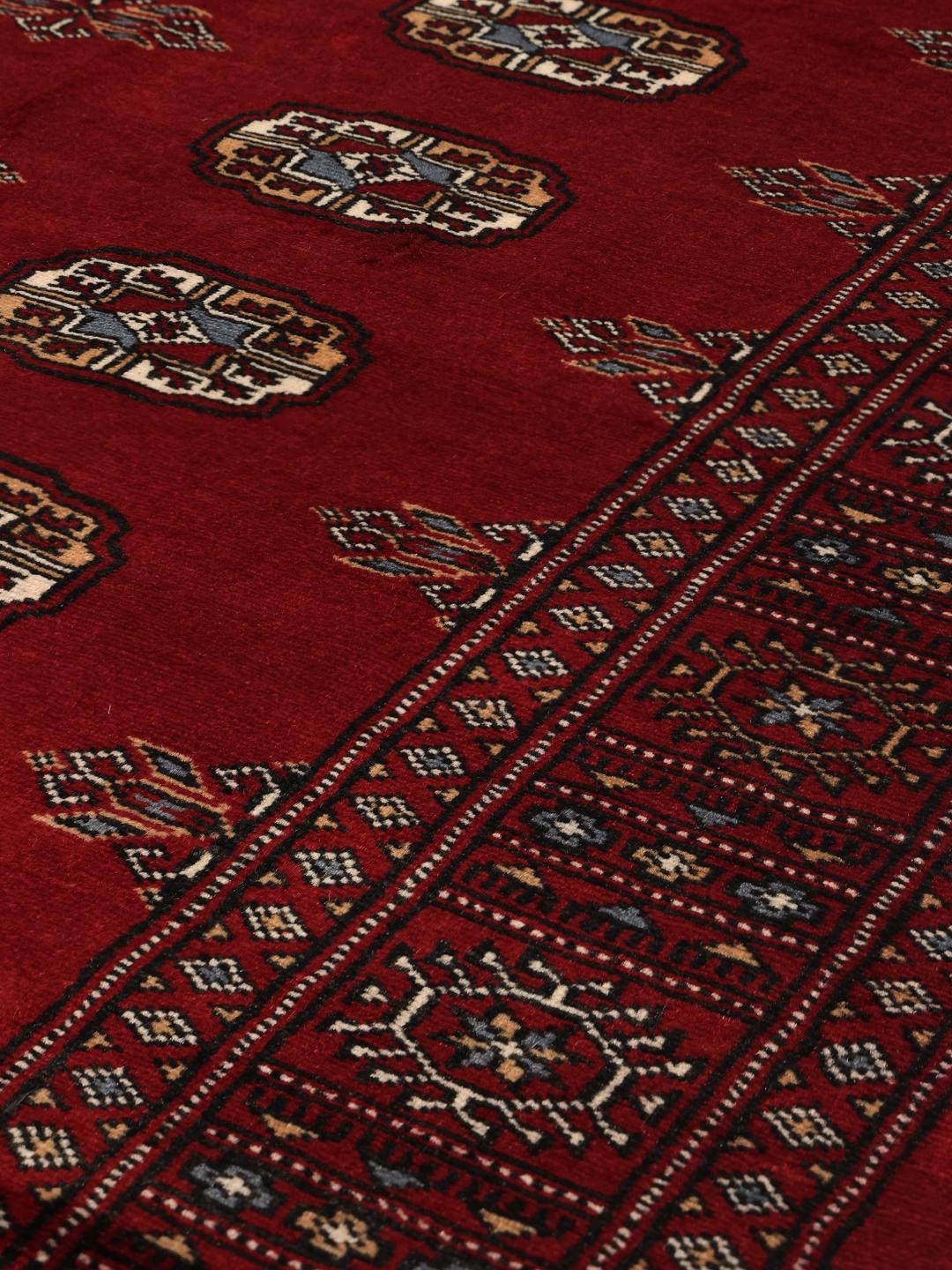 Handgeknoopt donkerrood wollen tapijt uit Pakistan met traditionele gul-patronen