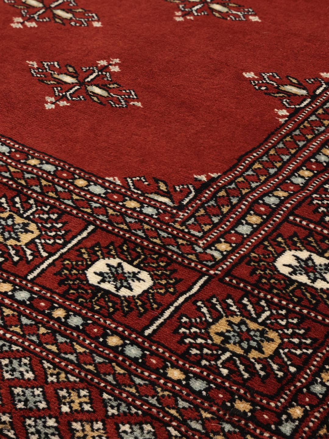 Hand-knotted Pakistani rug with a deep red field and repeating motifs
