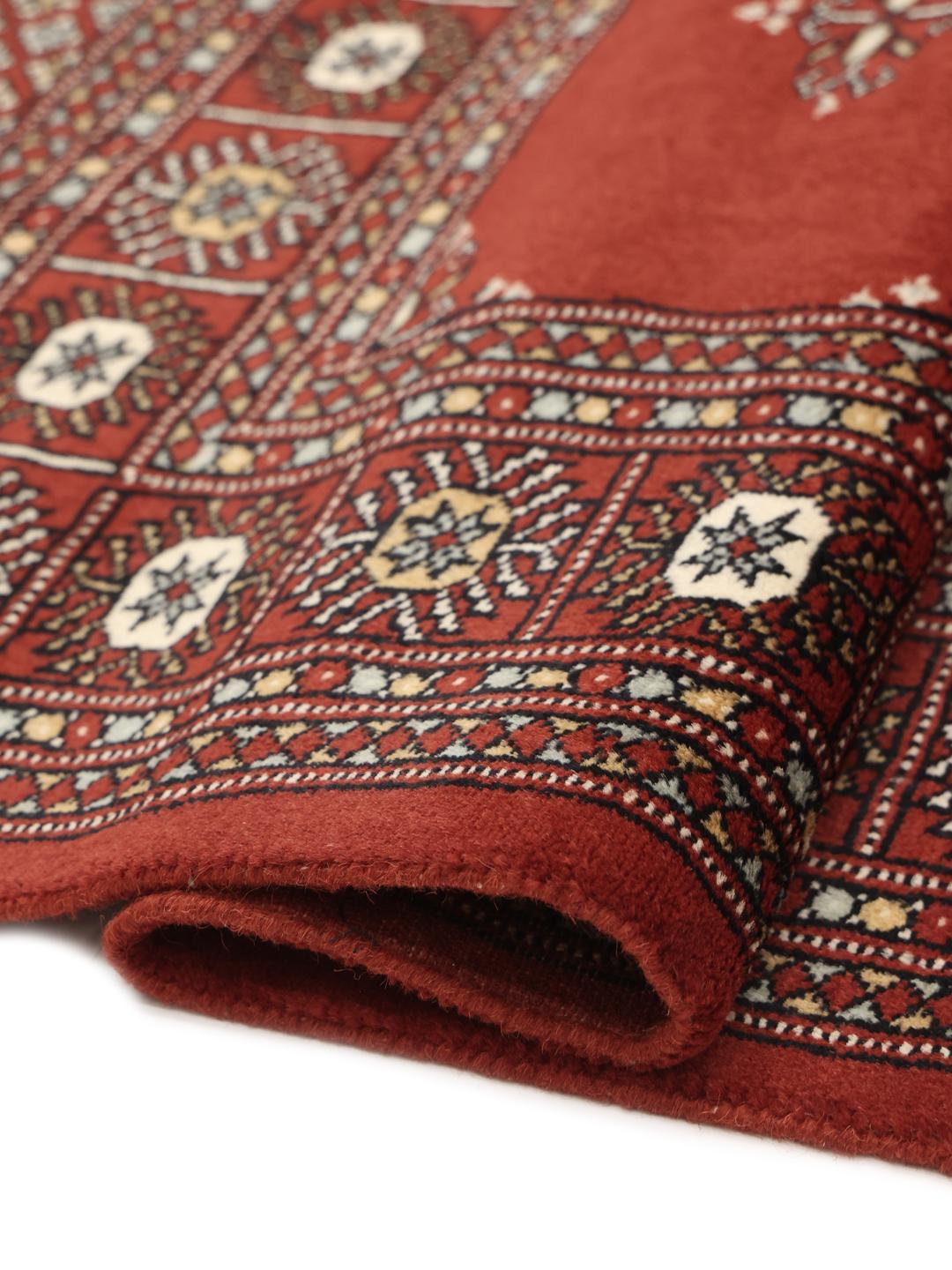 Hand-knotted Pakistani rug with a deep red field and repeating motifs
