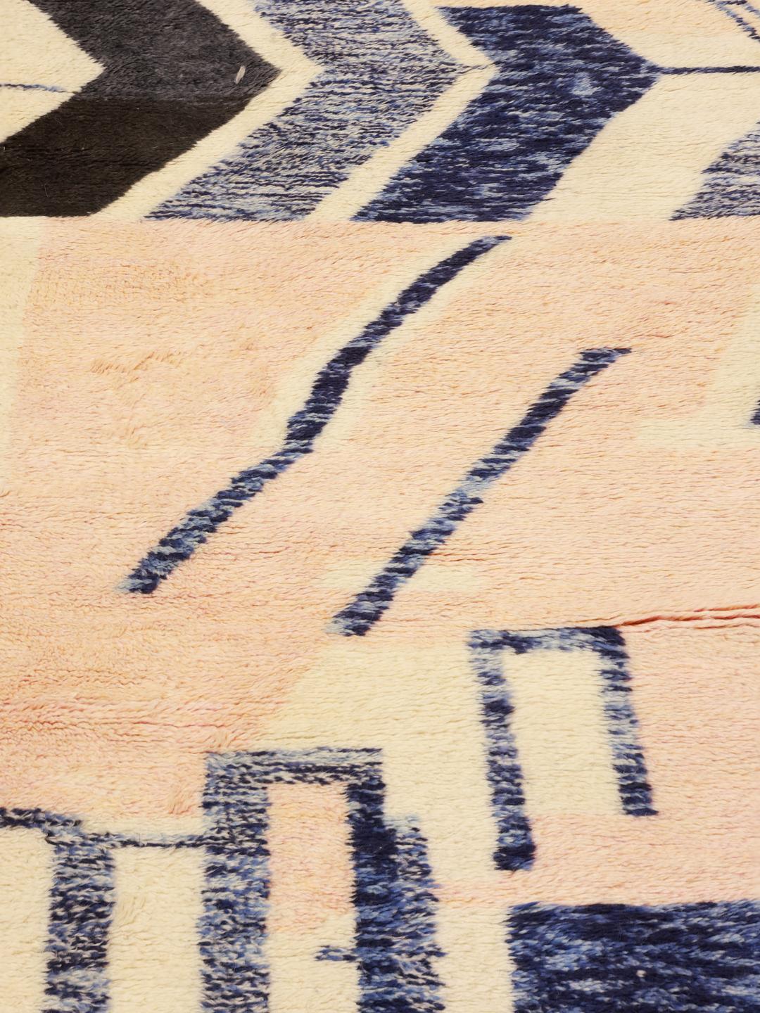 Een groot rechthoekig Marokkaans tapijt met een gedurfd, modern artistiek patroon in blauw, beige en zwart.