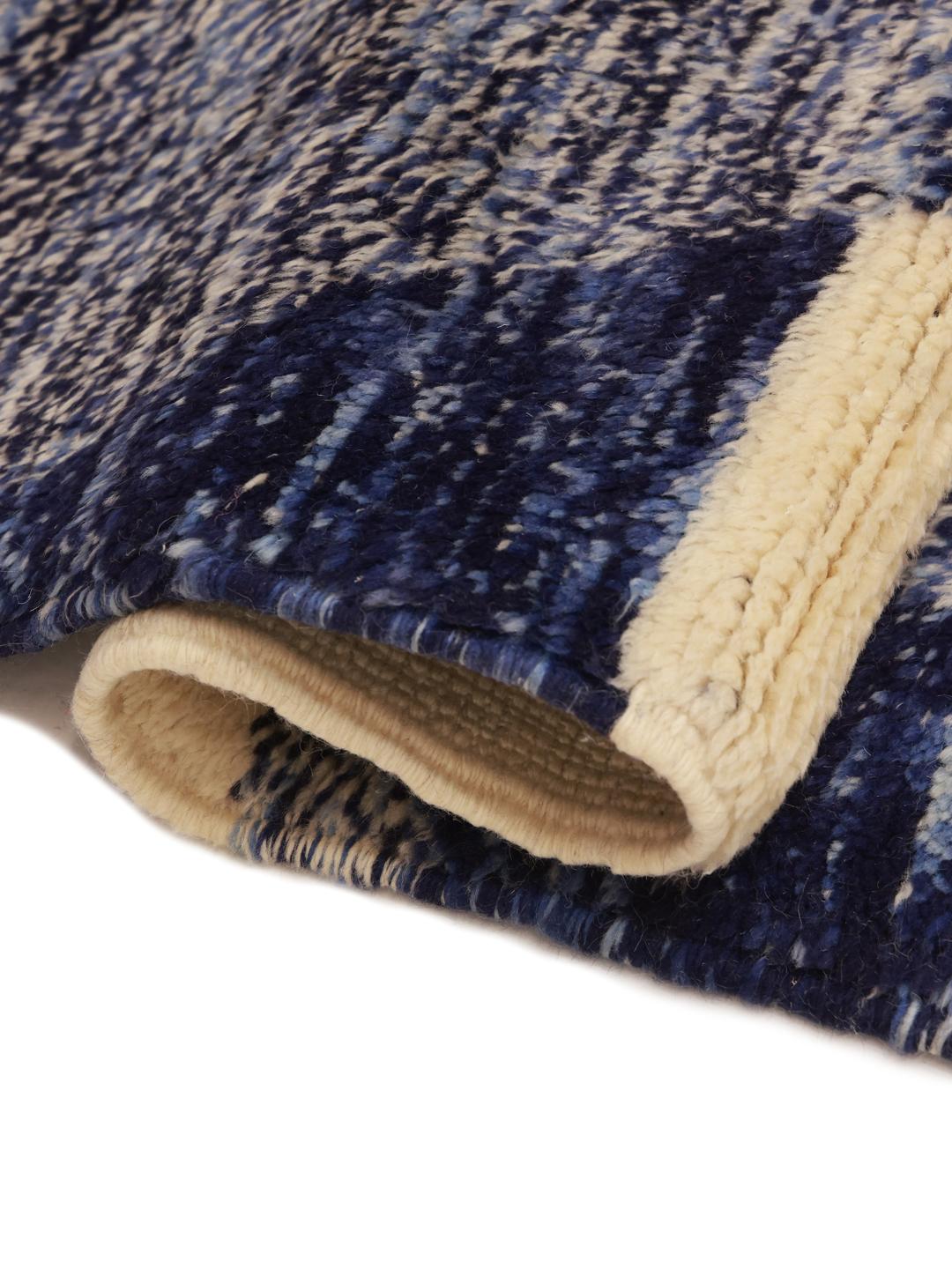 Een groot rechthoekig Marokkaans tapijt met een gedurfd, modern artistiek patroon in blauw, beige en zwart.