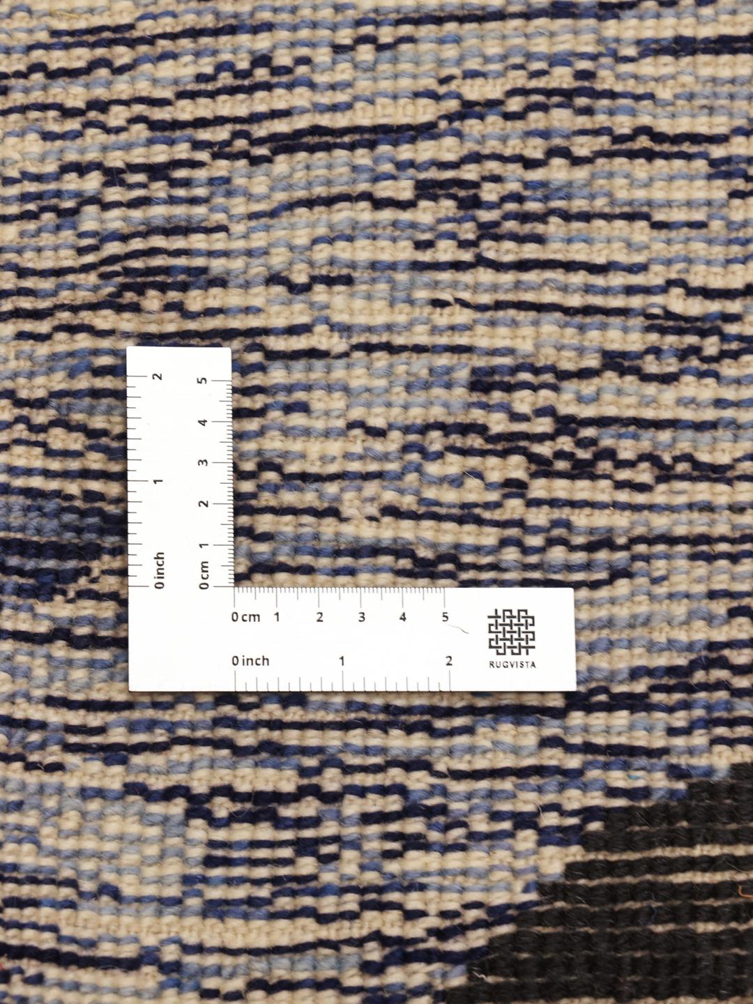 Een groot rechthoekig Marokkaans tapijt met een gedurfd, modern artistiek patroon in blauw, beige en zwart.