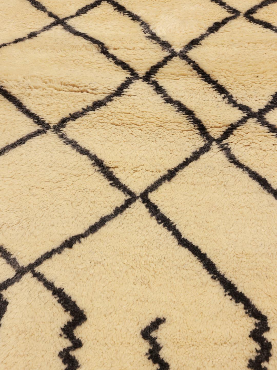 Handgeknoopt Marokkaans Berber Beni Ourain tapijt met geometrische zwarte lijnen op een beige achtergrond.