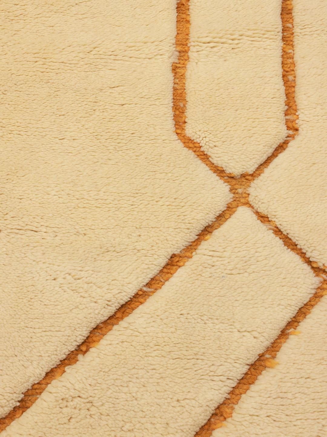 Een handgeknoopt Marokkaans Berber tapijt met een beige basis en mosterdkleurige geometrische lijnen.