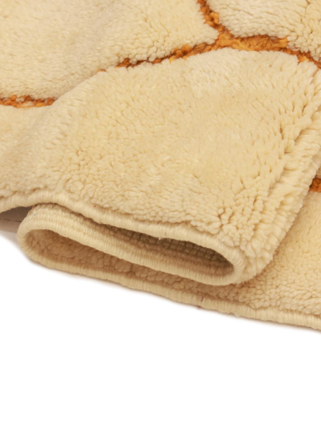 Een handgeknoopt Marokkaans Berber tapijt met een beige basis en mosterdkleurige geometrische lijnen.