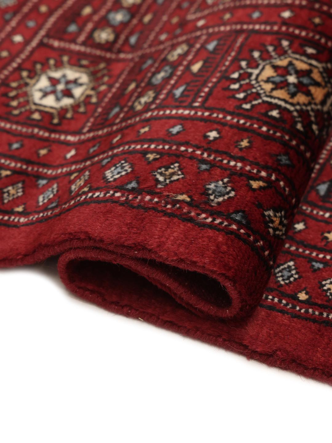 Hand-knotted Pakistani Bokhara rug in a deep red tone with traditional geometric patterns