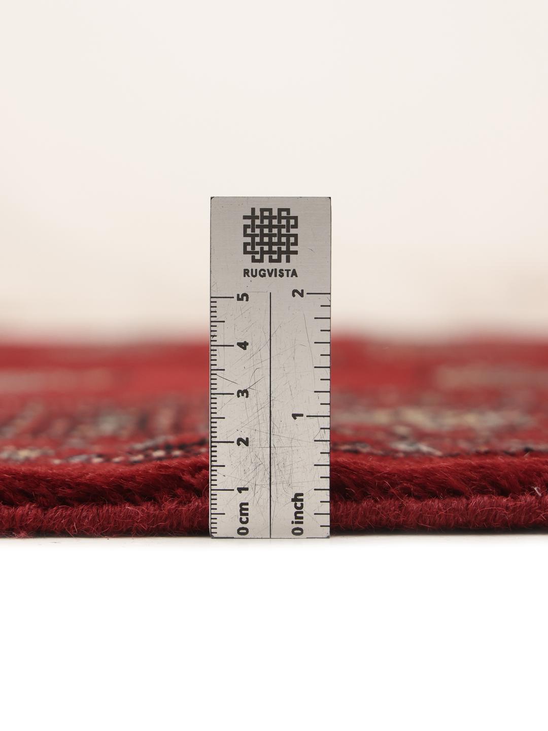 Hand-knotted Pakistani Bokhara rug in a deep red tone with traditional geometric patterns