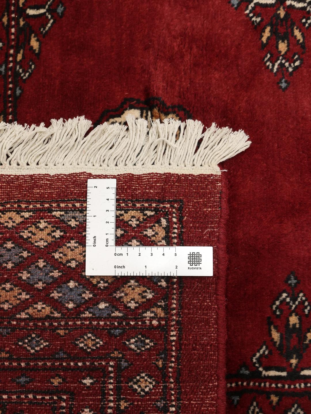 Hand-knotted Pakistani Bokhara rug in a deep red tone with traditional geometric patterns