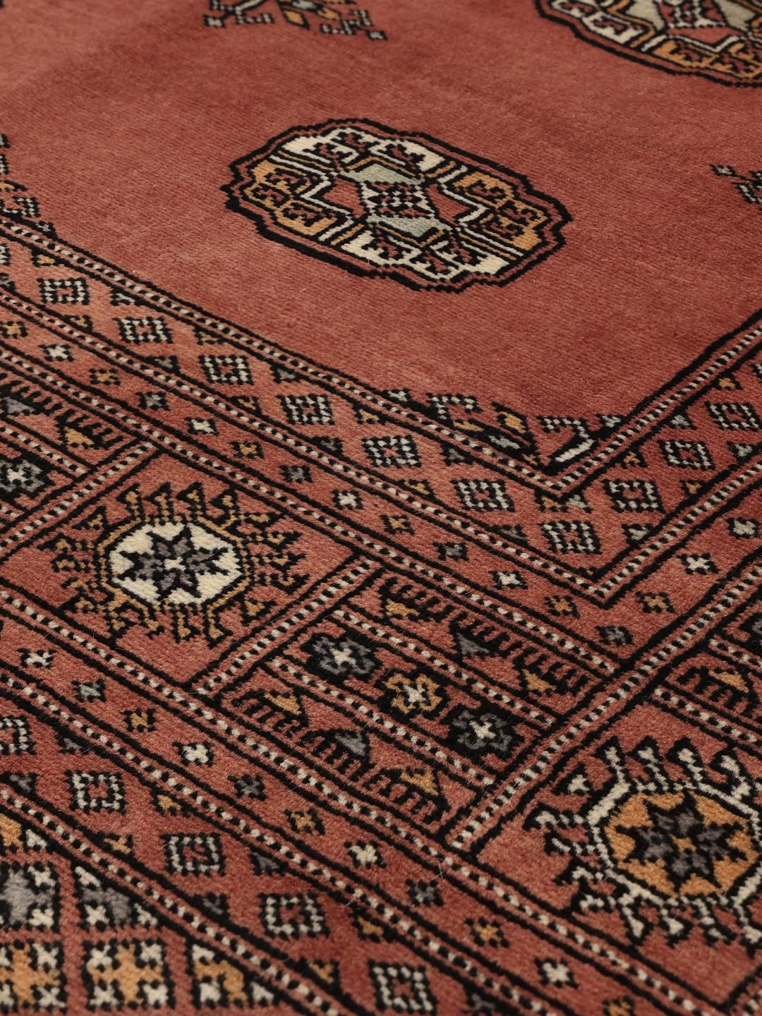 Håndknyttet firkantet tæppe fra Pakistan med et rigt rødt felt og traditionelle motiver.