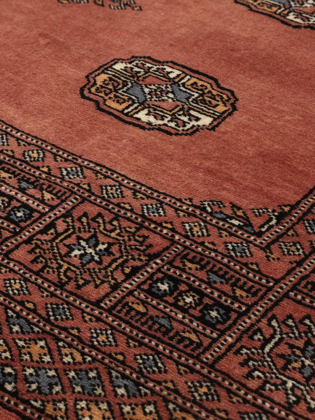 Hand-knotted dark-red Bokhara rug from Pakistan with traditional motifs