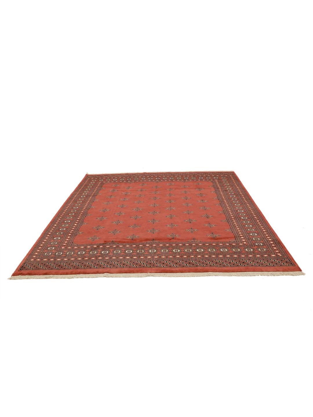 Een vierkant handgeknoopt Bokhara tapijt uit Pakistan met een dieprood veld en geometrische motieven.