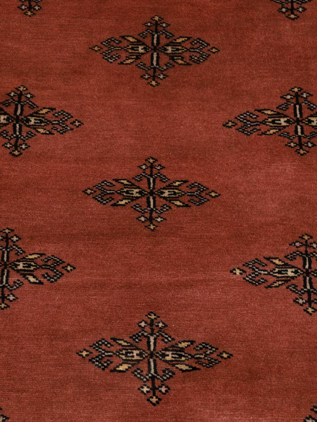 A hand-knotted Pakistani Bokhara rug with a warm red field and geometric motifs