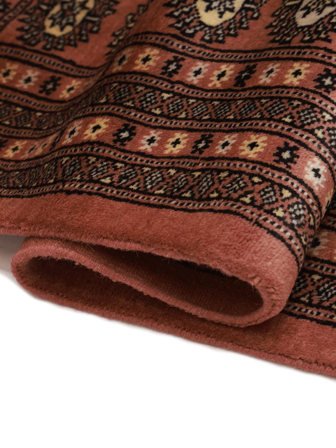 A hand-knotted Pakistani Bokhara rug with a warm red field and geometric motifs