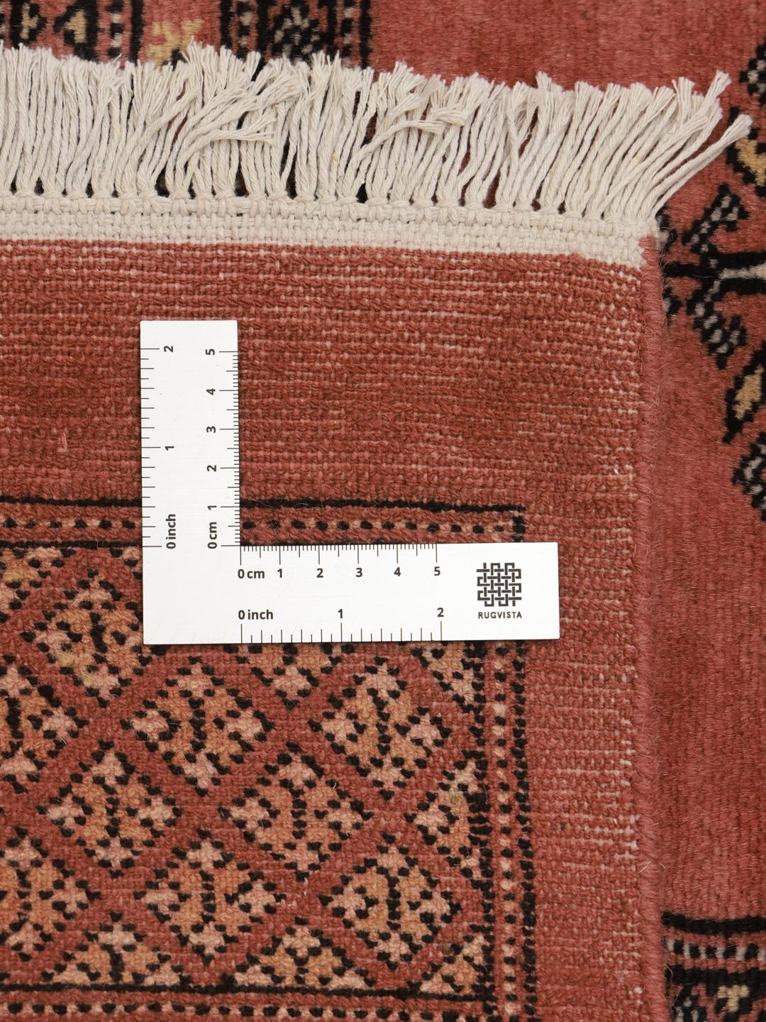 A hand-knotted Pakistani Bokhara rug with a warm red field and geometric motifs