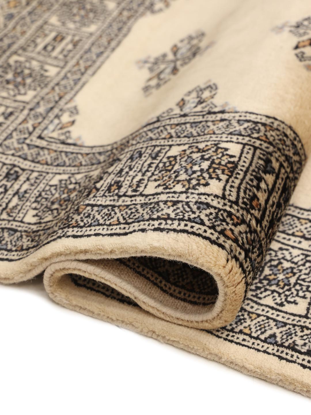 A long, cream-colored Pakistani hand-knotted runner with dark geometric motifs.